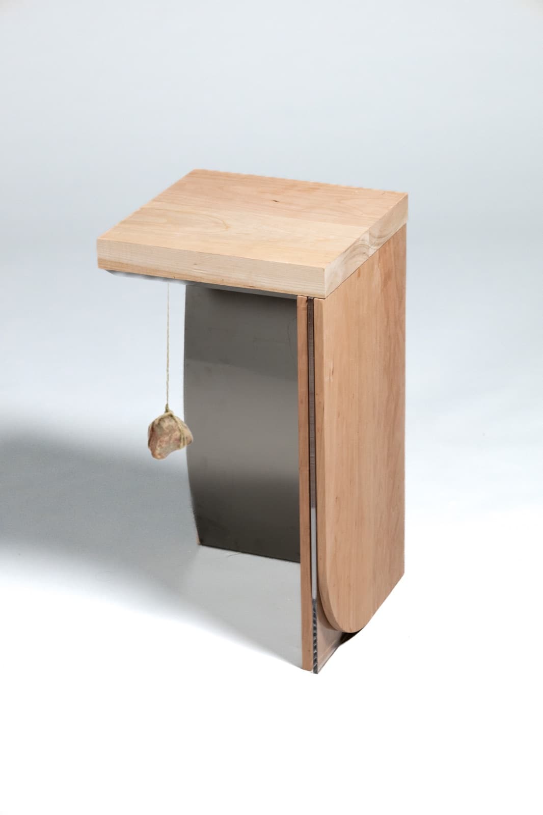 Side view of the wooden side table showing the steel panel and hanging stone pendant